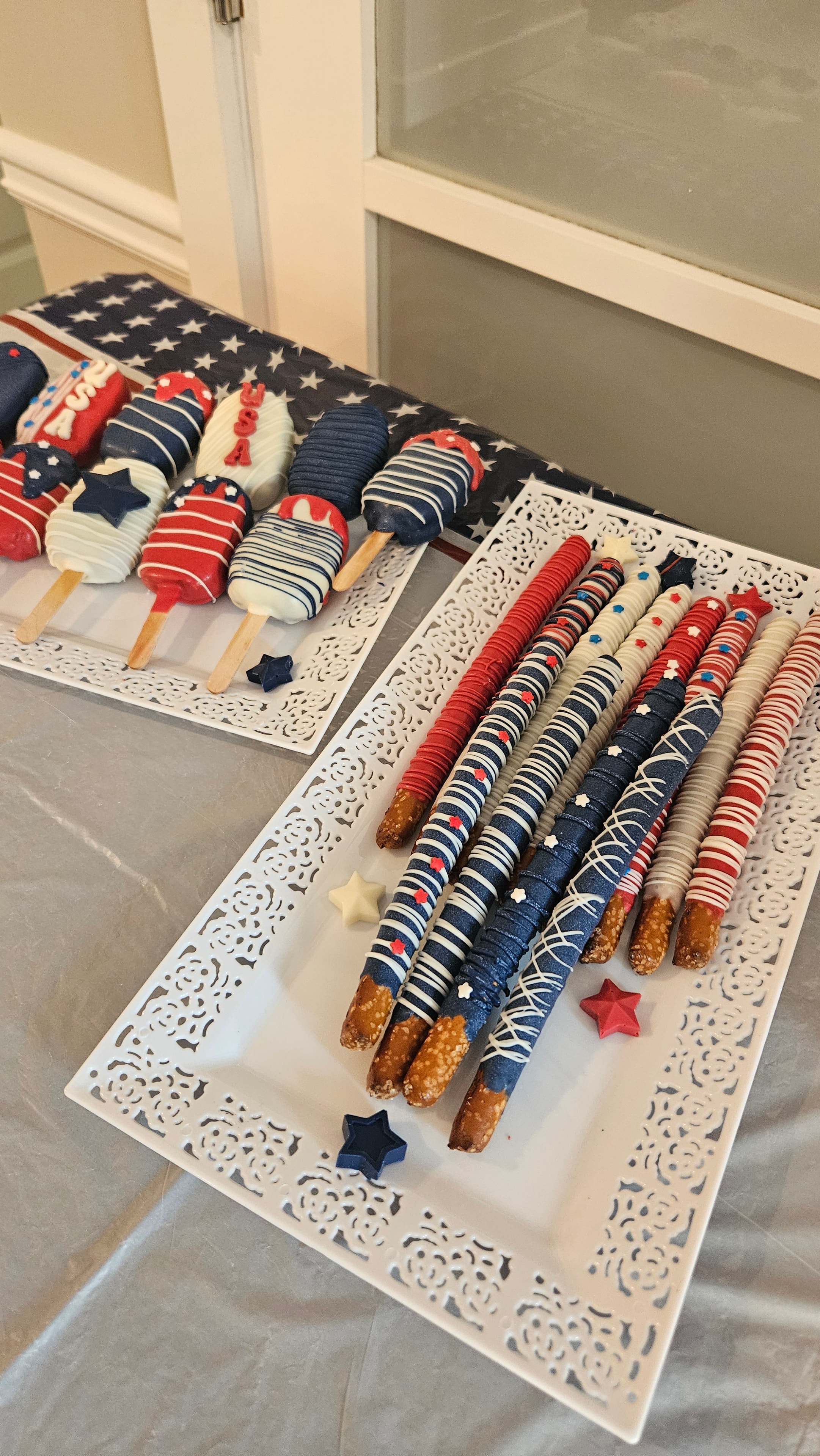 Patriotic red white and blue covered pretzel rods and cakesicles with star sprinkles