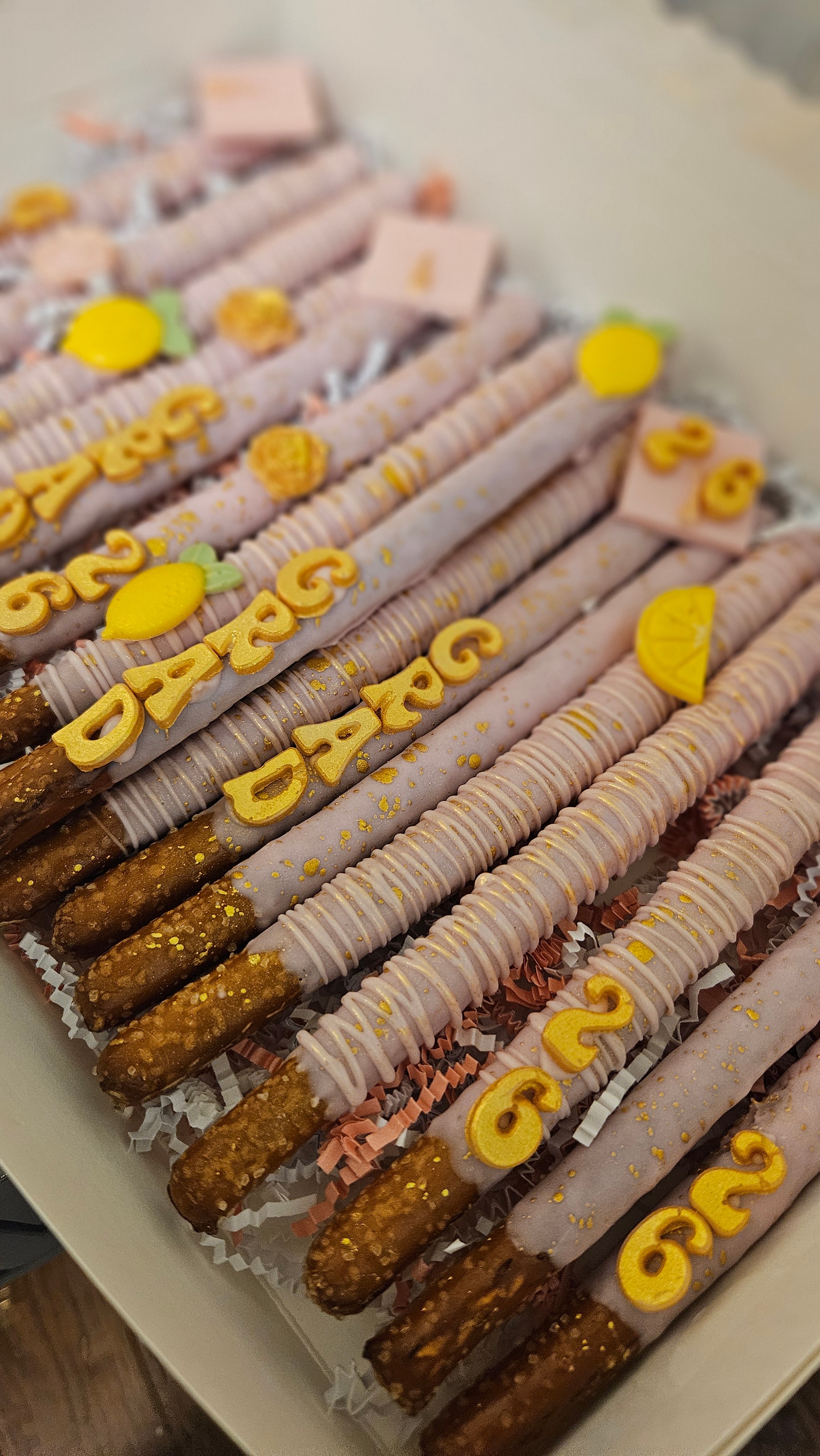 Graduation themed covered pretzel rods with gold GRAD lettering and lemon decorations
