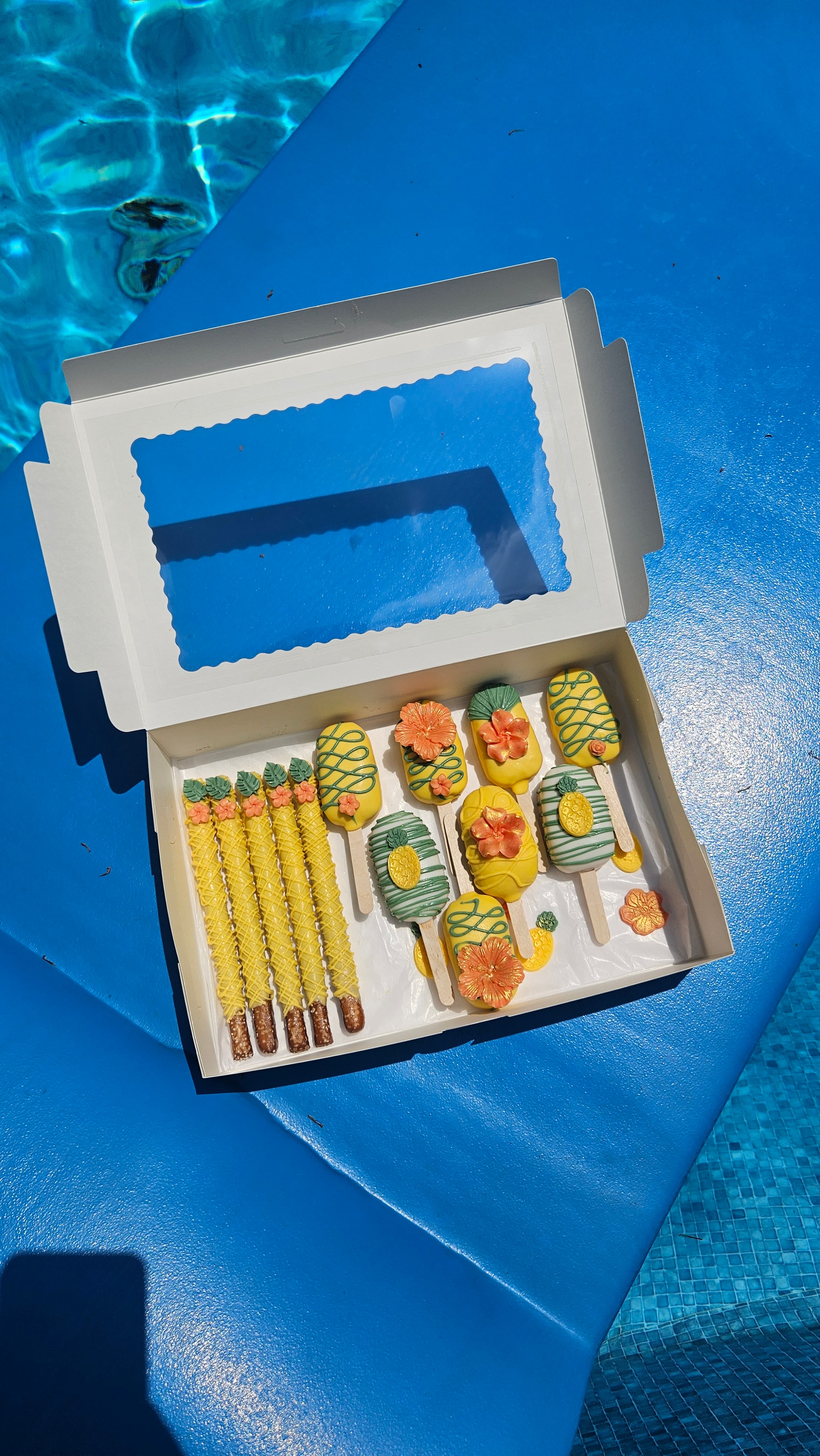 Tropical themed cakesicles and pretzels in pool box